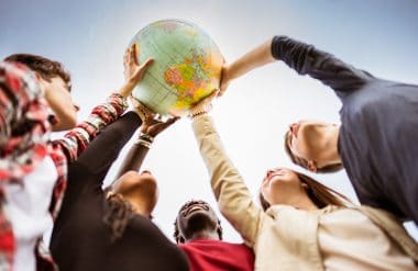 five people hold a globe to the sky